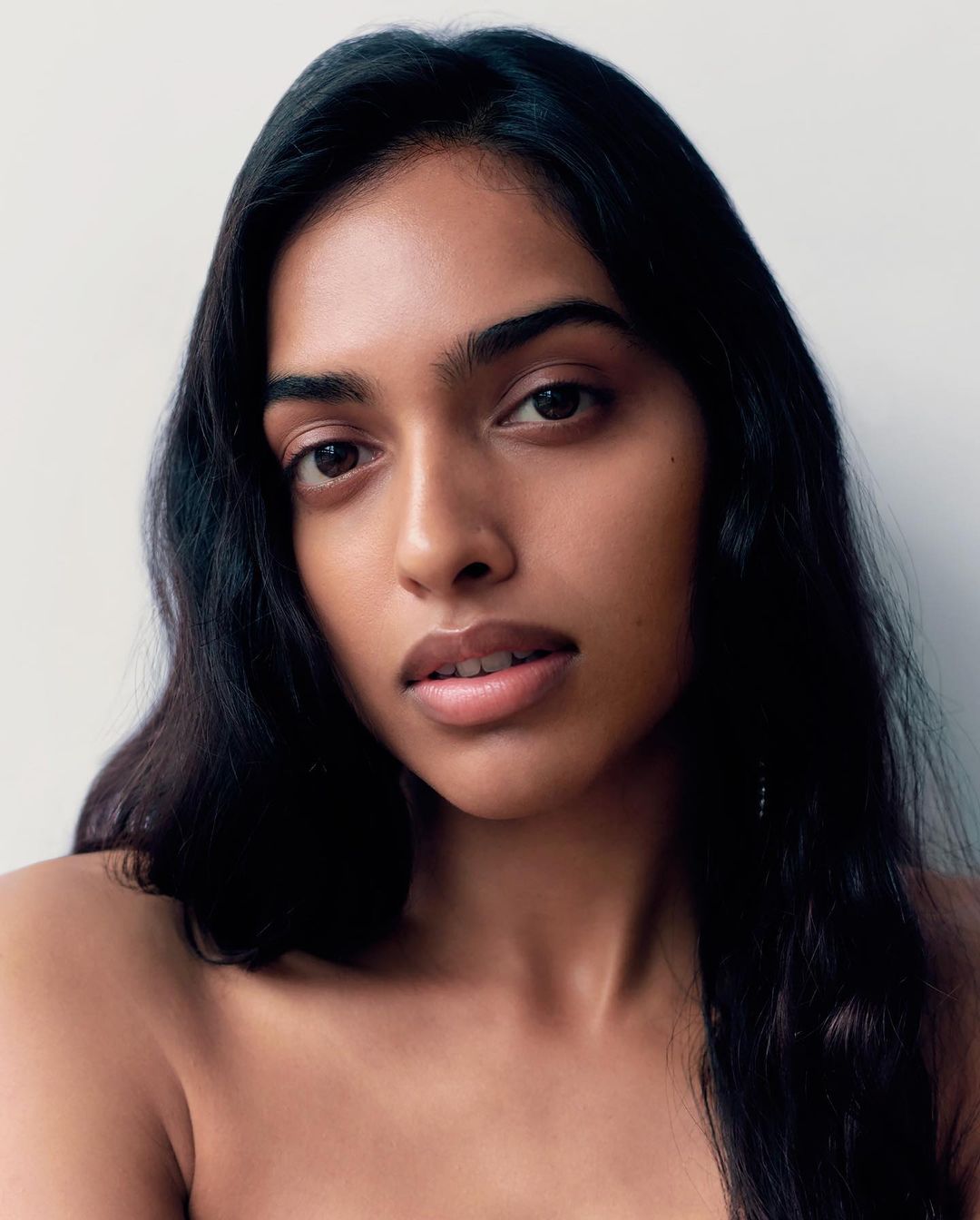 Close-up portrait of a woman with long dark hair and natural expression against a plain white background