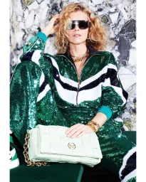 Woman in sequined green and white tracksuit wearing sunglasses holding a light green handbag by photographer Daniele Rossi.