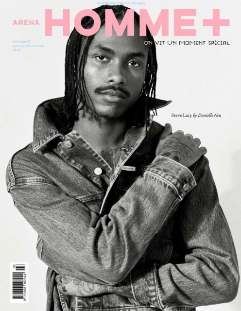 Black and white fashion magazine cover featuring a Black male model wearing a denim jacket with pink text overlay and visible tattoos.