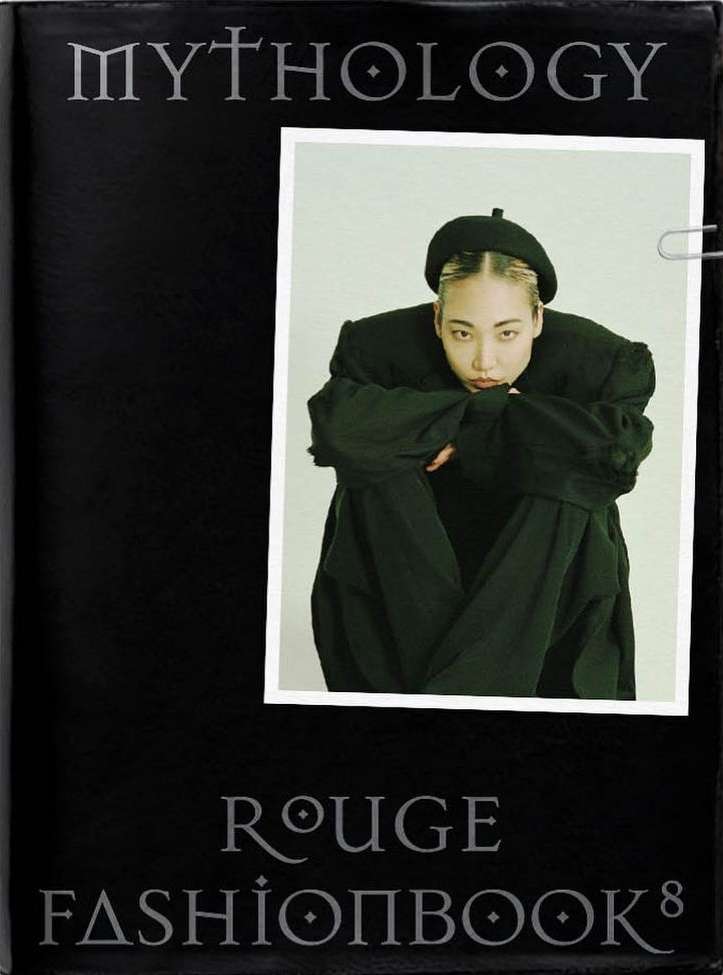 Fashion book cover featuring a portrait of an Asian woman wearing black clothing and a black beret, pinned inside the book with a paperclip.