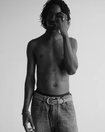 Portrait of a shirtless black man with dreadlocks wearing jeans against a neutral studio background