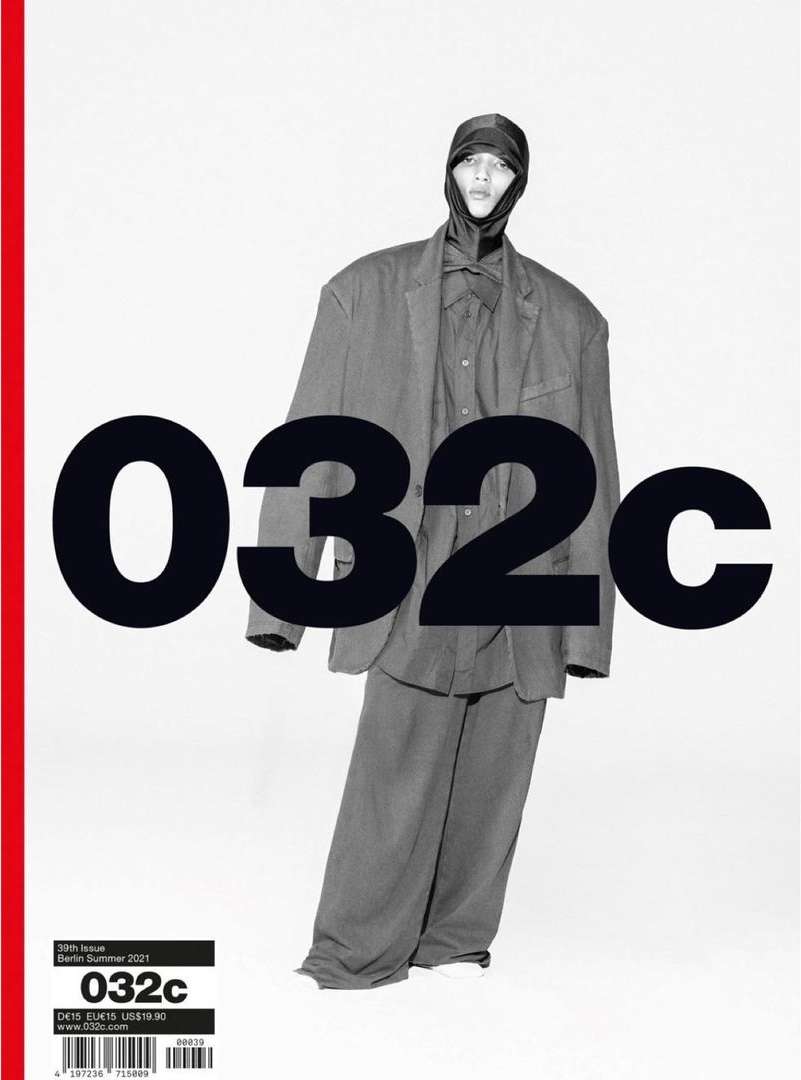 Magazine cover featuring a person in an oversized suit and head covering in front of a bold black and white title, with a red stripe.