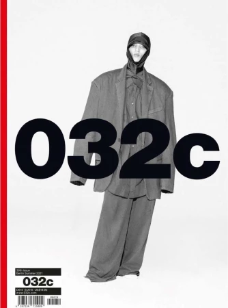 Magazine cover featuring a person in an oversized suit and head covering in front of a bold black and white title, with a red stripe.