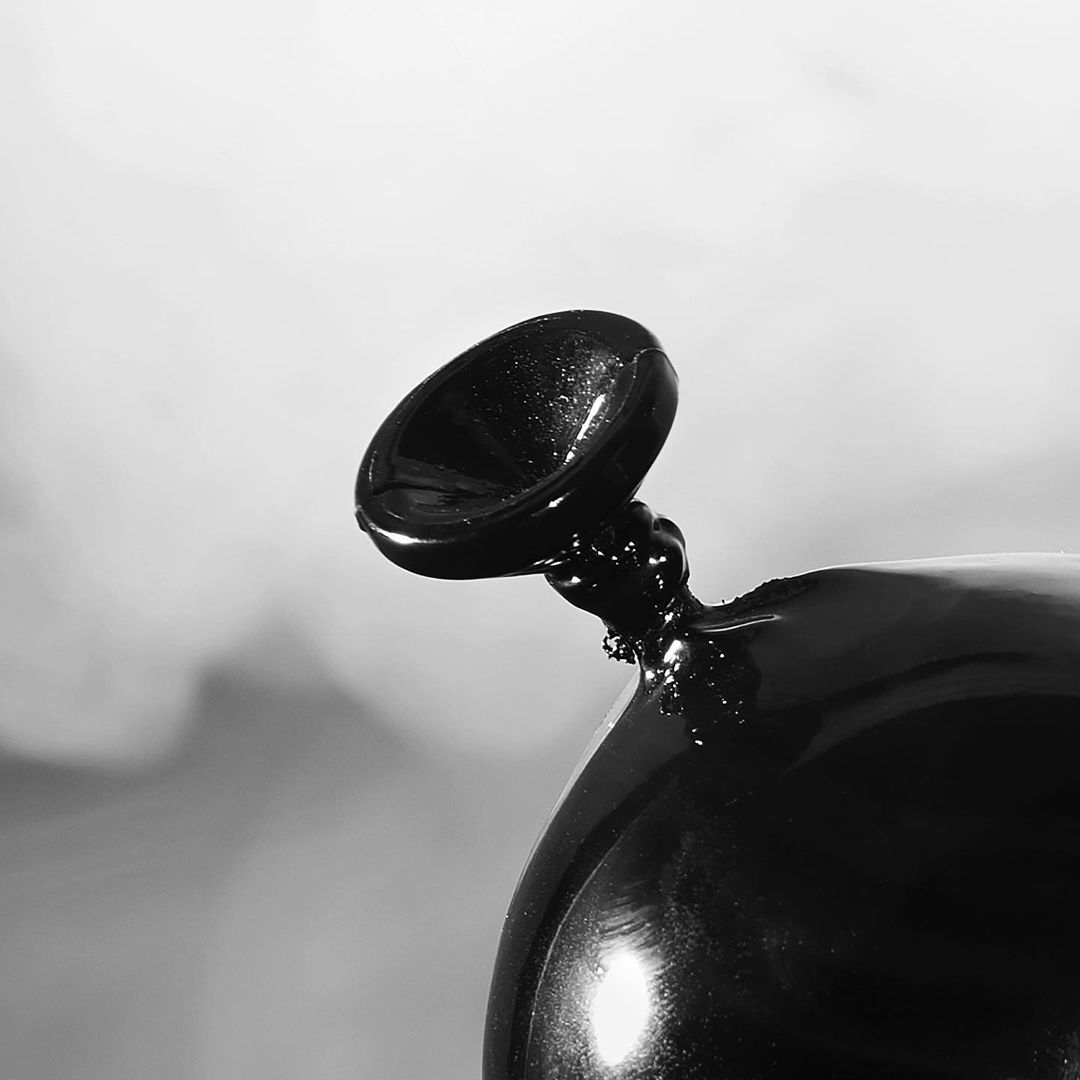 Monochrome image of a black balloon deflating against a soft grey gradient backdrop, showcasing a study in texture and form.