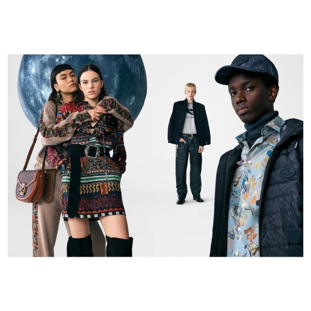 Fashion editorial shot featuring a group of three models wearing patterned jackets, dresses, and carrying a brown leather shoulder bag.