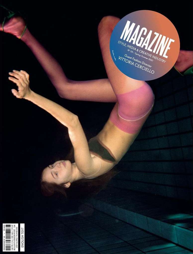 Magazine cover featuring a woman in hosiery and a black top, posing against a dark backdrop with geometric tile patterns.