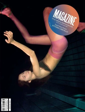 Magazine cover featuring a woman in hosiery and a black top, posing against a dark backdrop with geometric tile patterns.