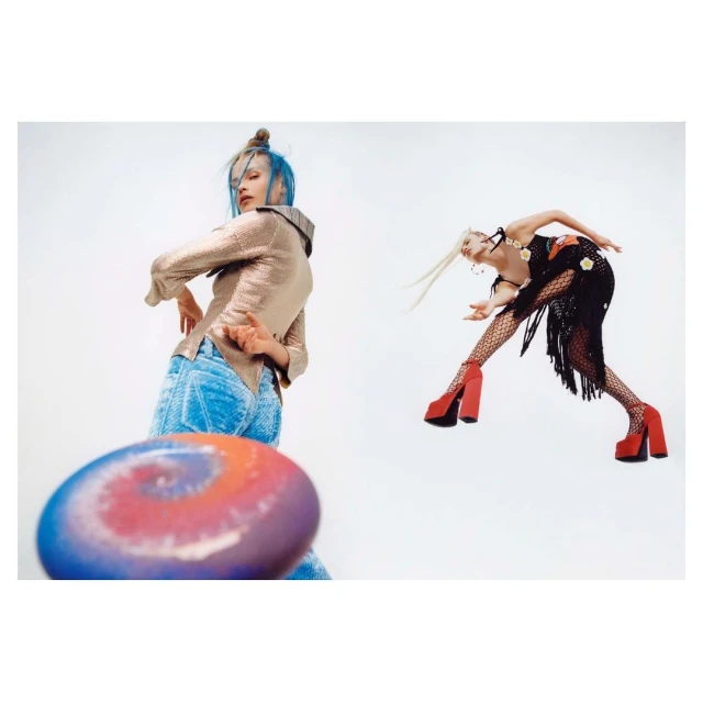 Two women strike dynamic poses in a bright studio, one throwing a colourful disc. The scene is captured with a low-angle perspective.