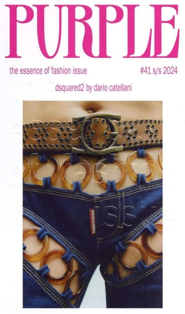 Fashion editorial featuring a partially exposed torso and hips, wearing embellished denim jeans with ring cutouts and a studded leather belt.