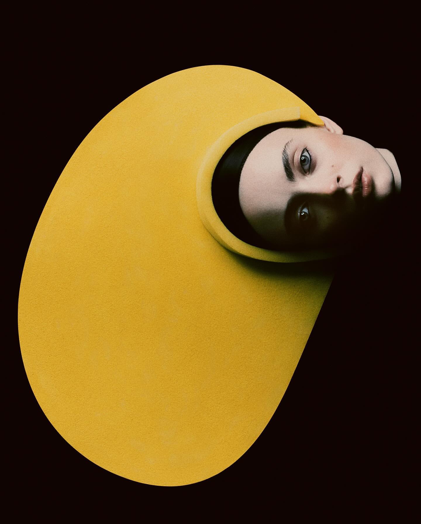 Close-up studio shot of a person wearing a yellow structural garment, set against a black background, showcasing unique textures and design.