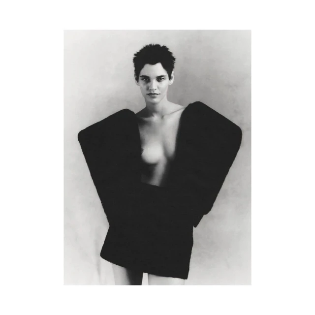 Monochrome portrait of a female fashion model with short dark hair wearing an oversized black jacket against a plain background.