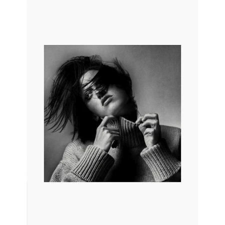 Black and white portrait of a woman wearing a ribbed turtleneck sweater, pulling at the collar in London