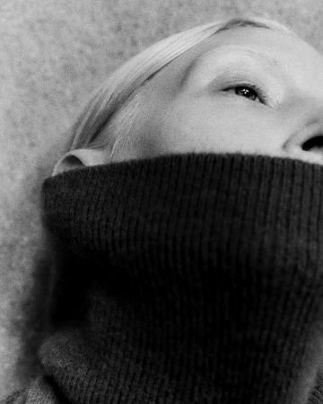 Close-up portrait of a model in a dark turtleneck sweater photographed in grainy monochrome by Darren Gwynn
