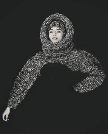 Monochrome portrait of a person wearing a thick knit hooded sweater framing their face, photographed by Darren Gwynn.