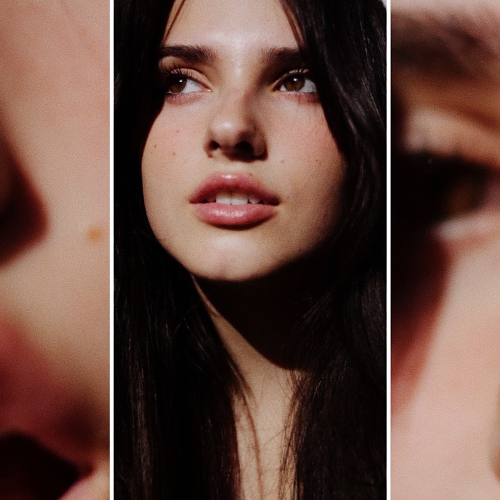 Close-up portrait of a young adult female with dark hair and fair skin looking off-camera in soft, moody lighting. Beauty shot.