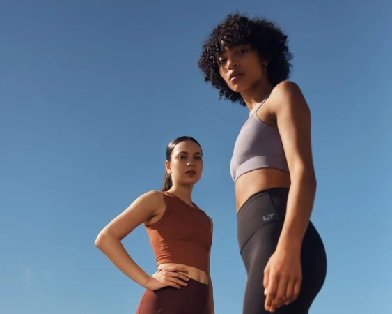 Low-angle shot of two female athletes wearing activewear against a clear blue sky by Dave Imms