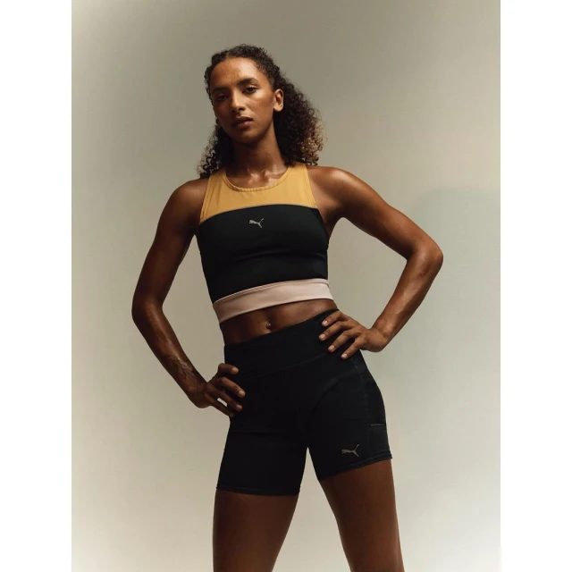 Athletic woman in Puma activewear poses in front of a neutral backdrop, showcasing sportswear and fitness lifestyle.
