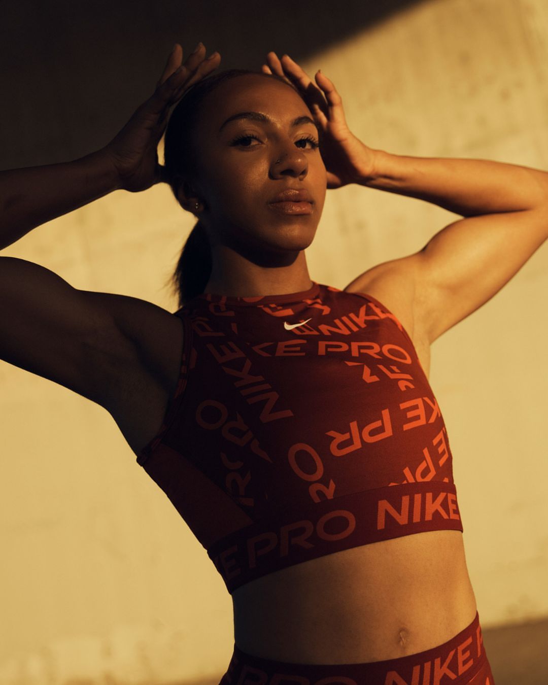 Athletic woman in Nike activewear poses against a neutral wall in a medium shot, showcasing fitness and sportswear fashion.