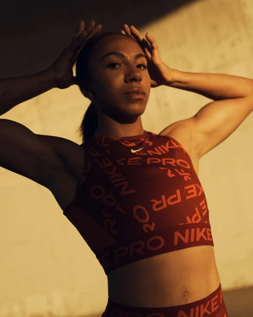 Athletic woman in Nike activewear poses against a neutral wall in a medium shot, showcasing fitness and sportswear fashion.