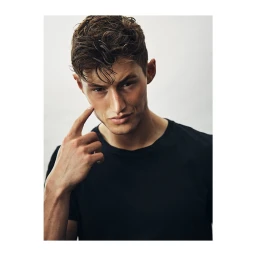 Portrait of a young man wearing a black t-shirt against a plain white background, photographed by Dave Imms.