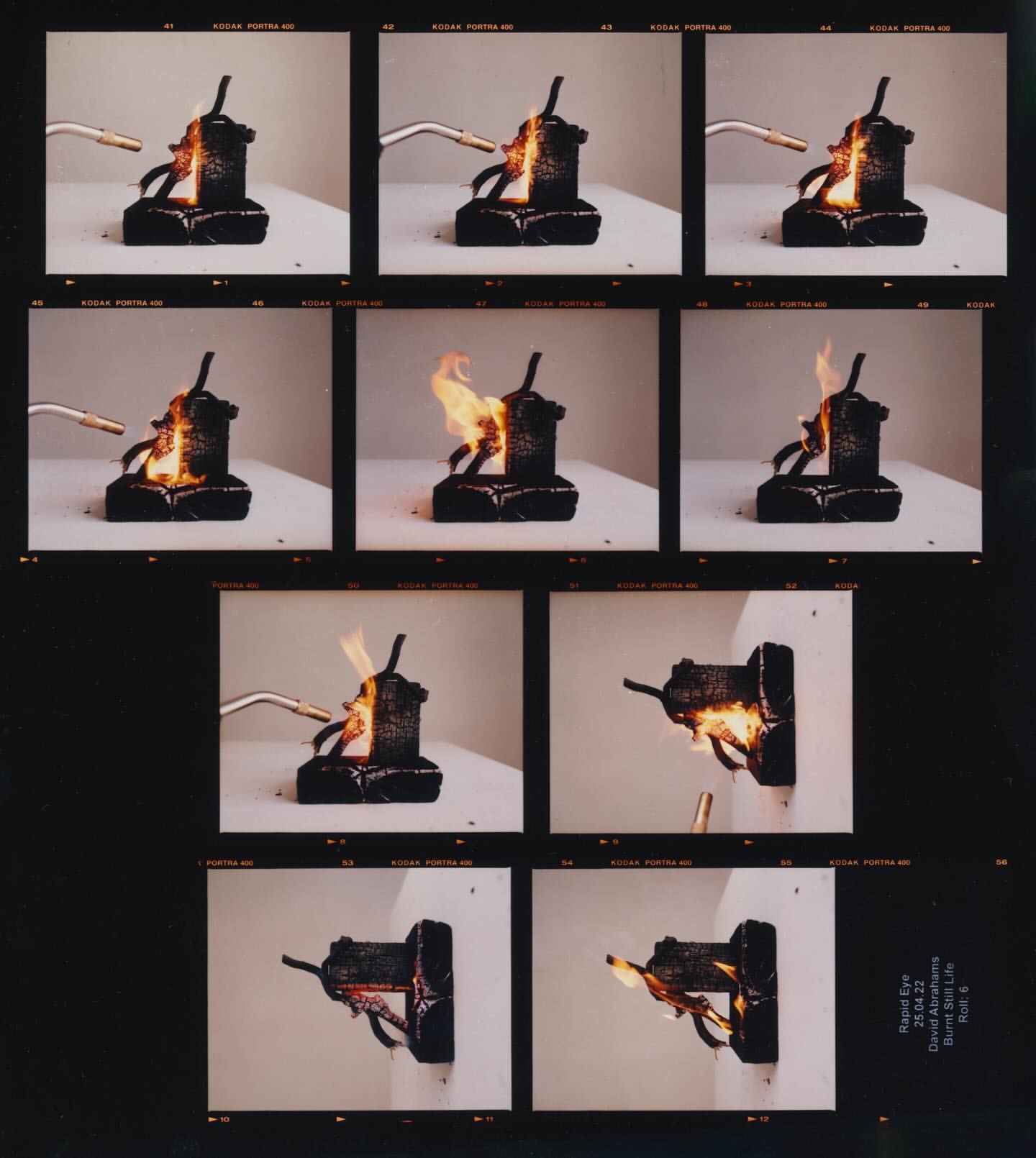 Sequence of images showing a black, geometric object being set on fire by a small blowtorch against a white background in a studio setting.