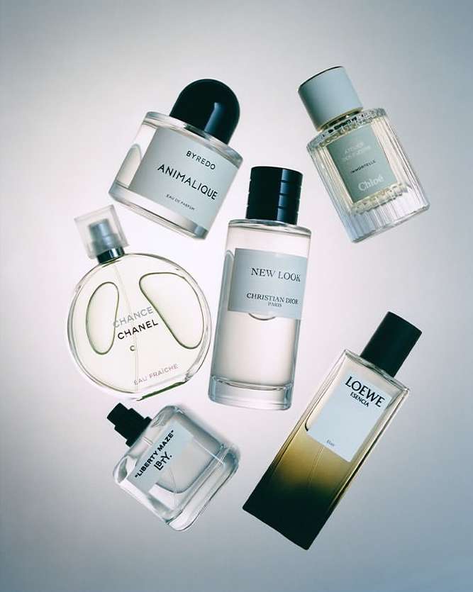 Arrangement of perfume bottles including Byredo, Chanel, Christian Dior, Loewe, and Chloe brands against a gradient background.