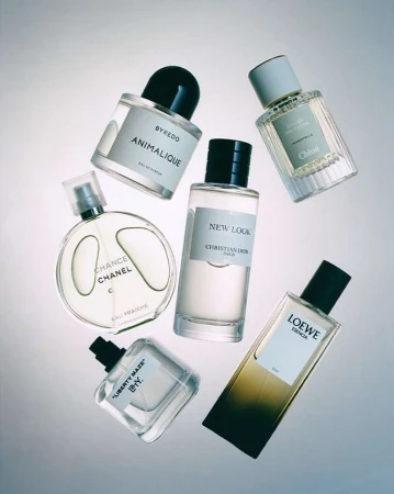 Arrangement of perfume bottles including Byredo, Chanel, Christian Dior, Loewe, and Chloe brands against a gradient background.