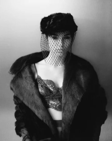Monochrome portrait of a woman wearing a fur hat with a mesh veil and a heavy fur coat by David Abrahams
