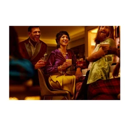 Group of friends laughing and holding cocktails inside a warmly lit bar photographed by David Boni