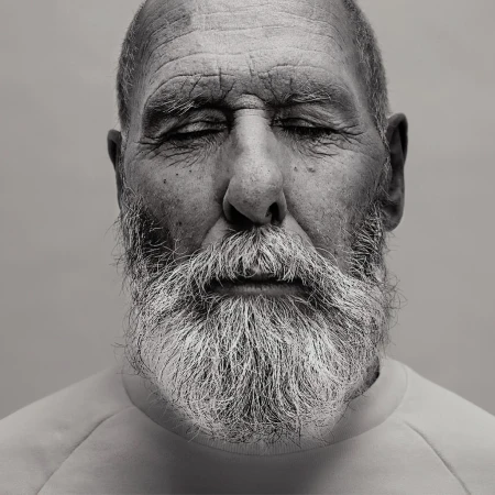 Close-up portrait of an elderly man with closed eyes and a full grey beard, photographed by David Boni.
