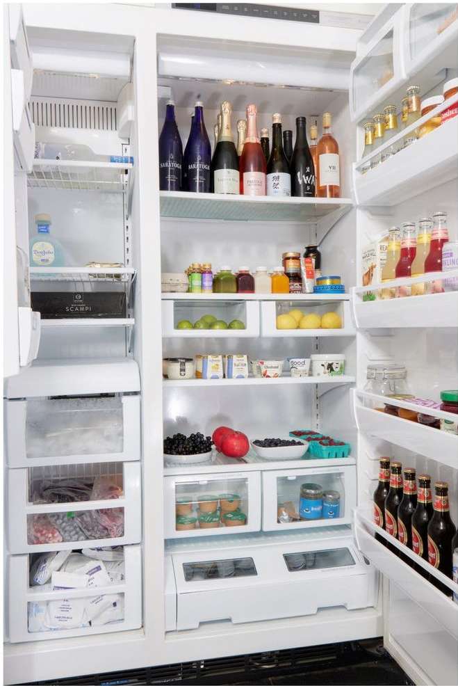 Refrigerator fully stocked with colorful beverages and food items neatly arranged on shelves and in drawers, highlighting freshness and organization.
