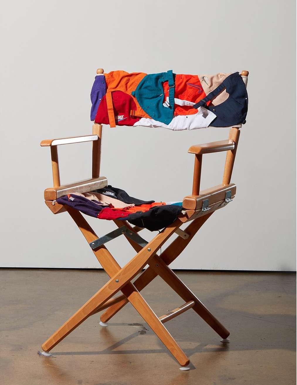 Director's chair upholstered with multicolored fabric pieces in photo studio setting, visually striking piece of furniture, unique decor.