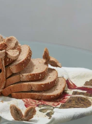 Close up of sliced brown bread arranged on a patterned towel against a plain background photographed by David Brandon Geeting