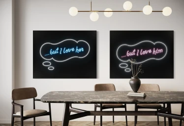 Two large dark art prints with glowing neon speech bubbles reading but I love her and but I love him hanging in a dining room