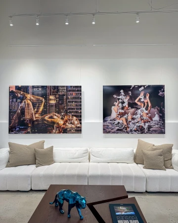 Modern white sectional sofa in an art gallery interior with two large David Drebin photography prints hanging on the wall.