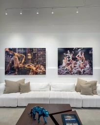 Modern white sectional sofa in an art gallery interior with two large David Drebin photography prints hanging on the wall.
