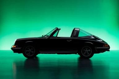Black vintage sports car photographed in profile against a vibrant green studio backdrop by photographer David Fischer.
