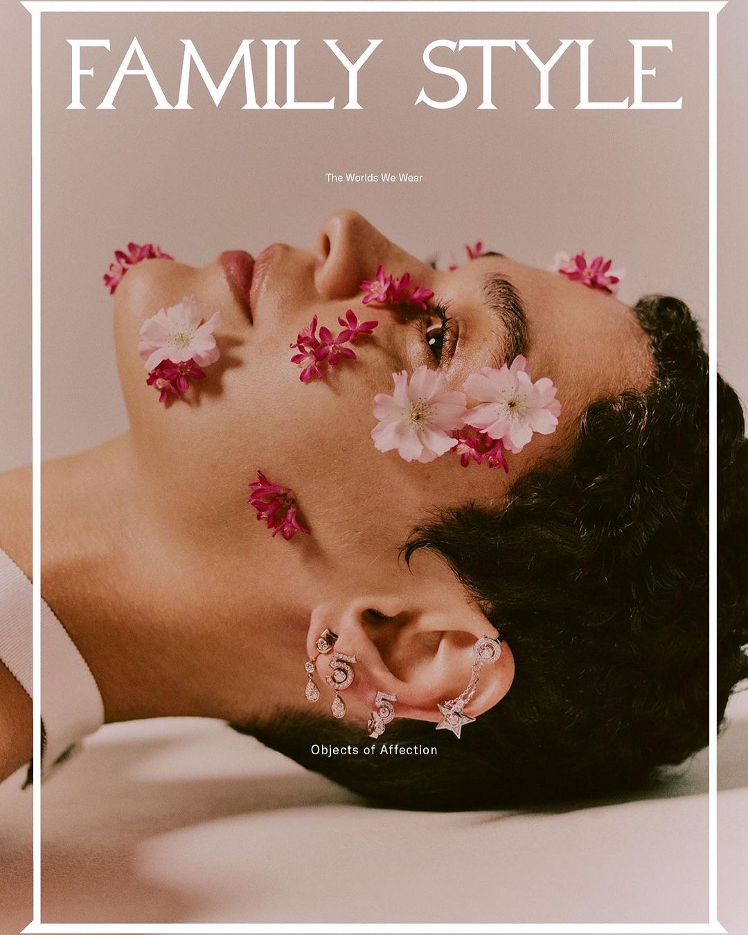 Fashion magazine cover featuring a person with flowers and jewelry on light pink backdrop. The image has editorial and beauty style.