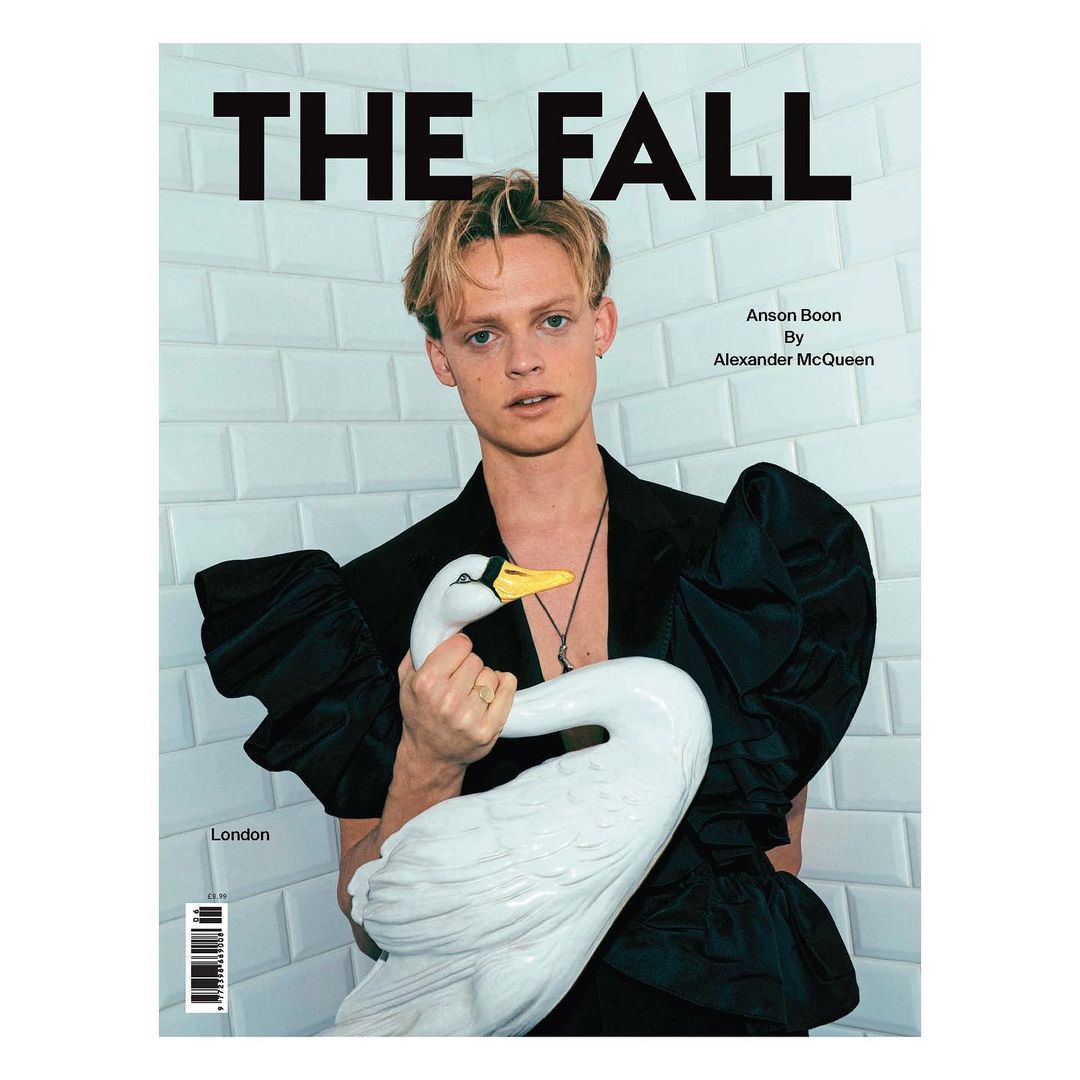 Magazine cover featuring Anson Boon in a black ruffled outfit, holding a white swan statue, set against a tile background.