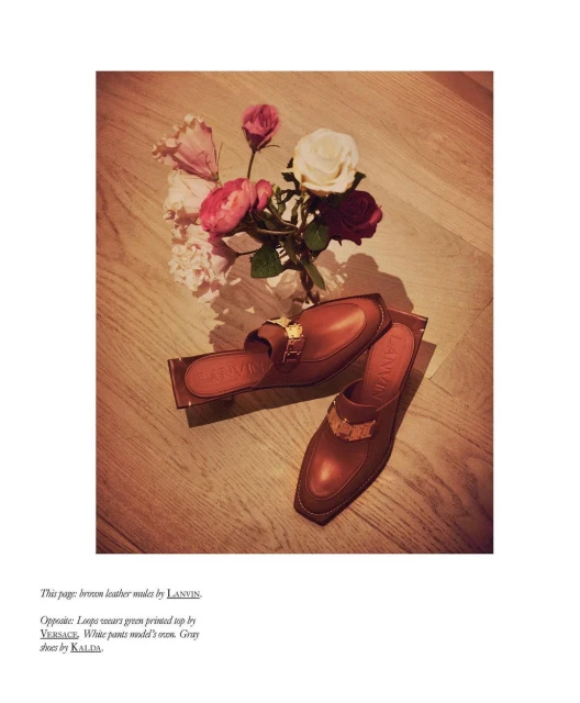 Elevated view showcases Lanvin leather mules with gold buckle detail, paired with pink and white roses on a light wood floor.