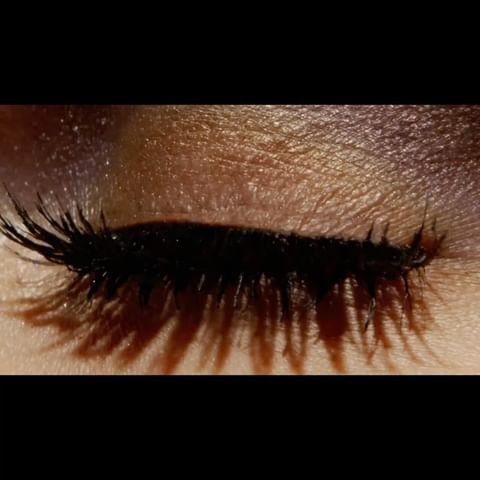 Close-up shot of a single closed eye with long, dark lashes and brown eyeshadow on fair skin. Beauty and makeup concept.
