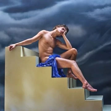 Nude male figure sits contemplatively on stairs, draped with blue fabric, against dramatic cloudy sky, artful and evocative.