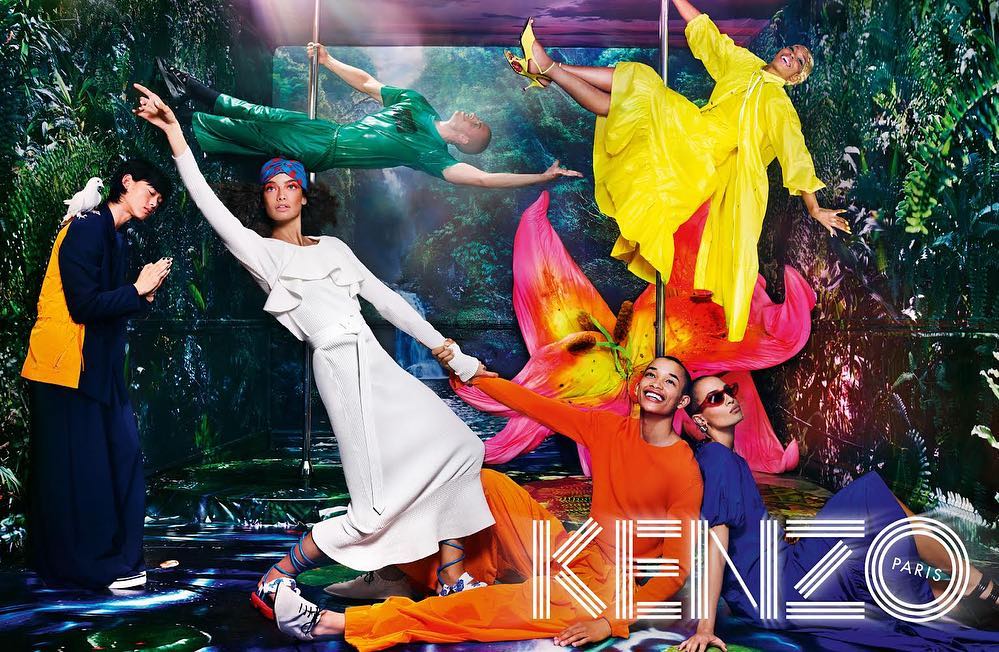 Fashion editorial featuring diverse models in bright outfits against a surreal floral and jungle backdrop, shot in a vibrant, artistic style.