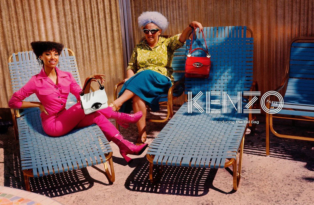 Two stylish women pose with Kenzo handbags in an outdoor setting, showcasing a fashion campaign with vibrant colors and retro aesthetics.