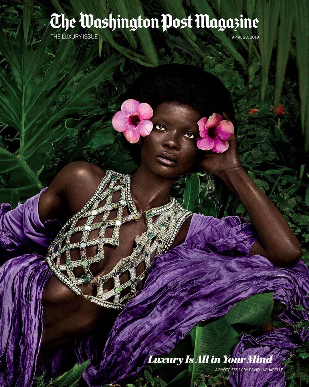 Magazine cover of a dark-skinned woman with pink flowers in her hair, wearing an elaborate jeweled top and purple draped sleeves.