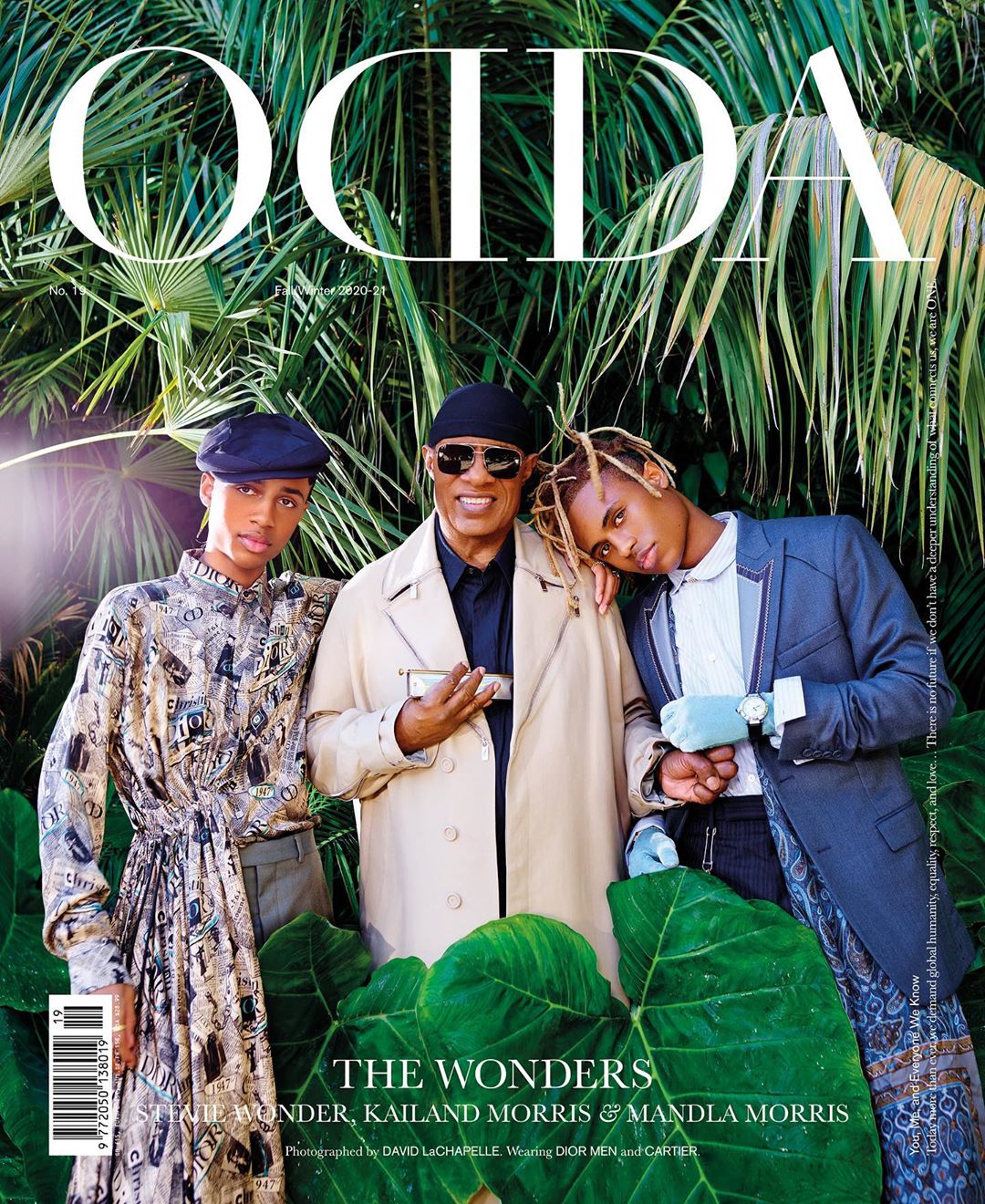 Magazine cover featuring Stevie Wonder with two young men against a tropical green backdrop, promoting music and fashion.