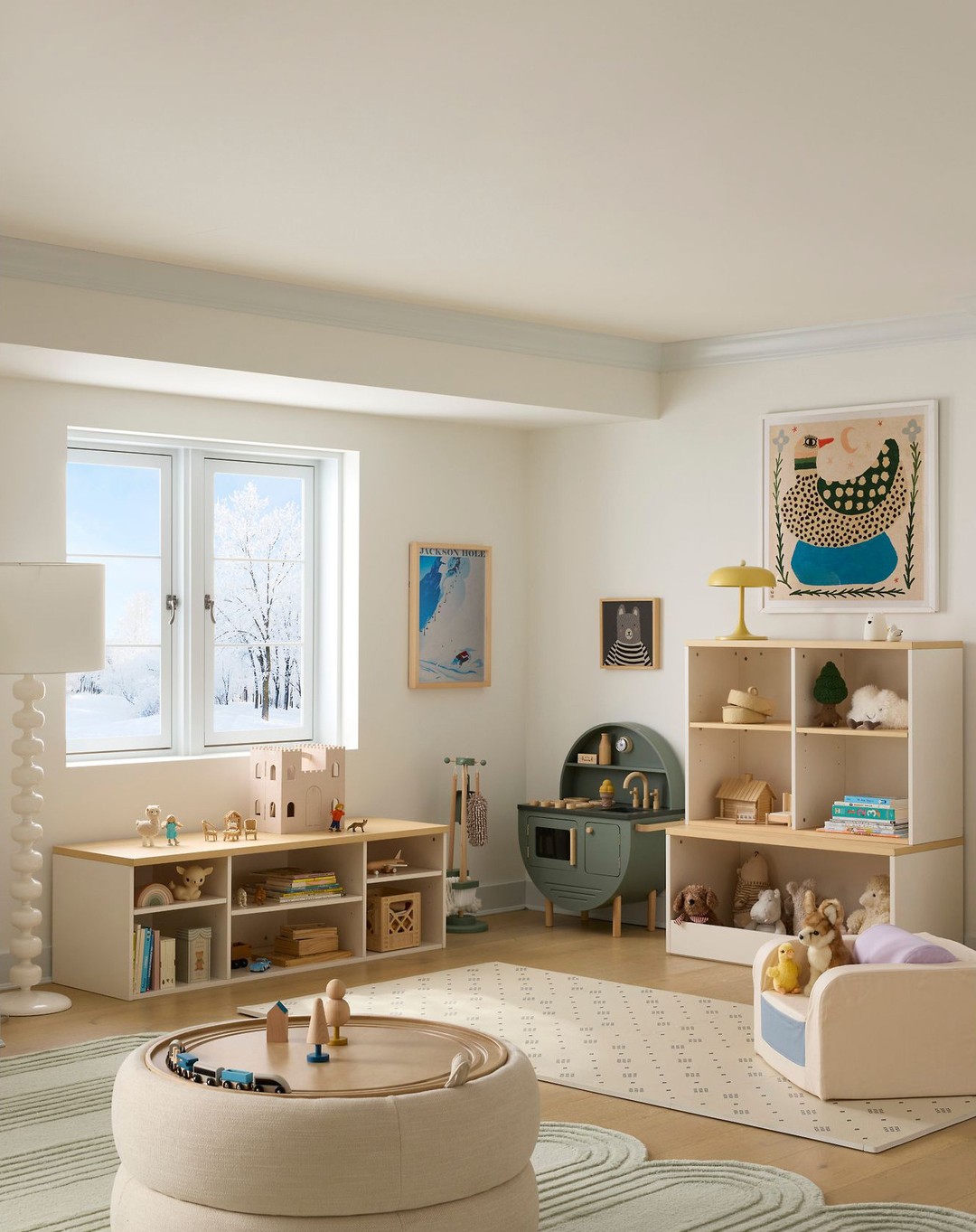 Cozy and bright kids' playroom interior featuring wooden toys, shelving units, play kitchen, round ottoman, and ample natural light.