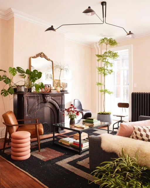 Living room interior featuring a black fireplace, patterned rug, brown leather chair, and decorative plants in a cozy, stylish setting.