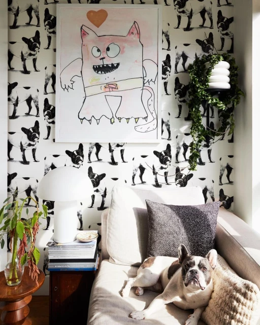 French bulldog lounges on a sofa in a room featuring cartoon cat art and dog-themed wallpaper, creating a playful interior design.