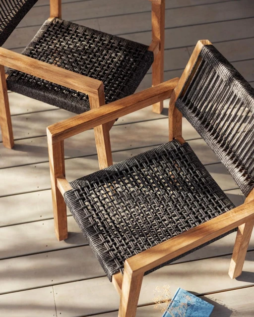Elevated shot of three wooden-framed chairs with woven seats, showcasing modern outdoor furniture on a wood surface with a blue book.